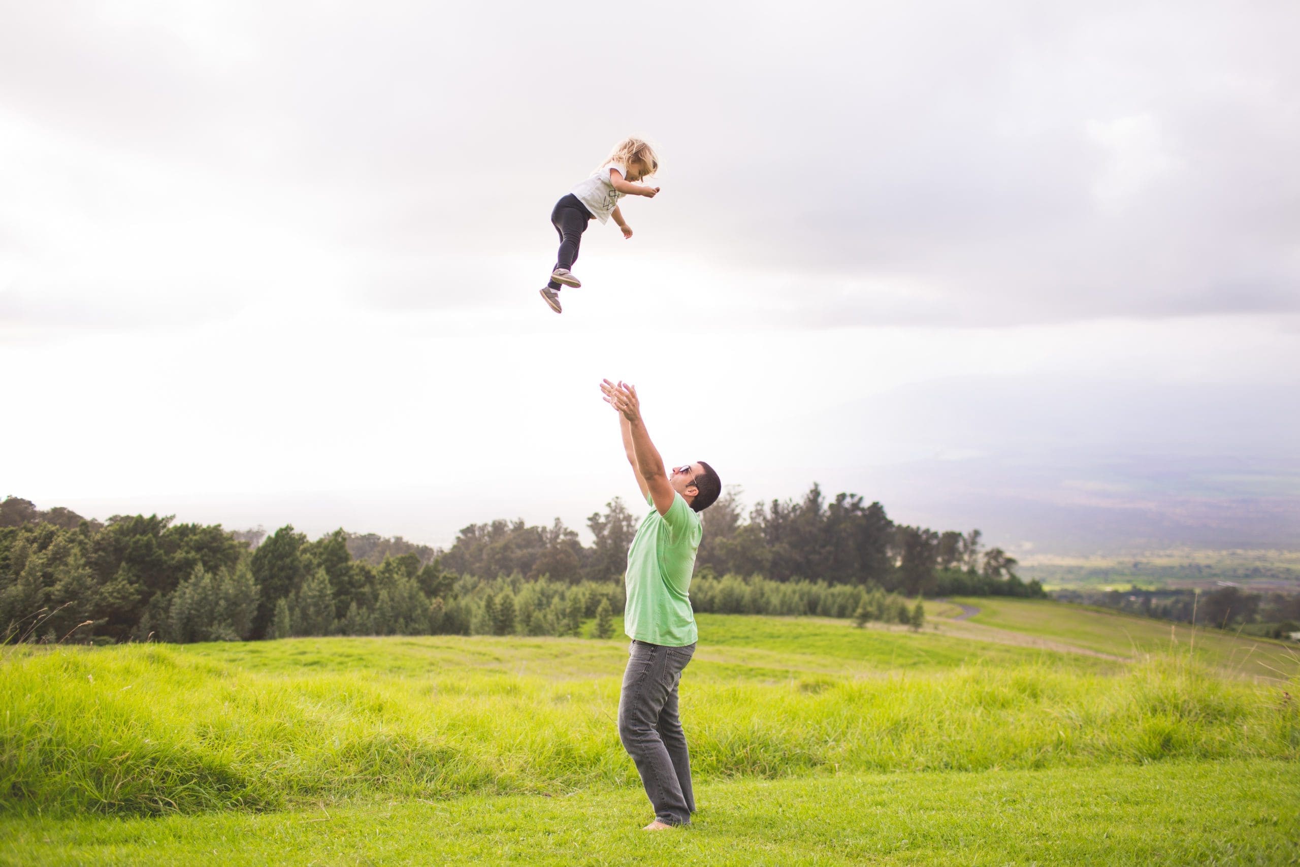 man throwing child in air with beautiful landscape