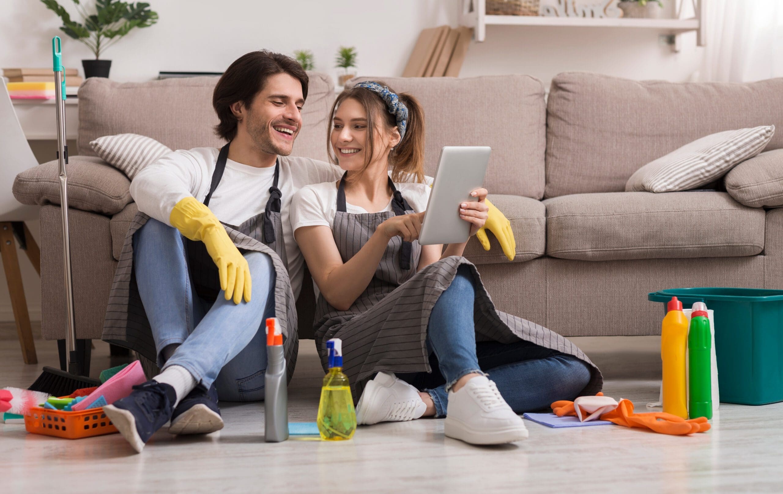 Cheerful,Young,Couple,Relaxing,With,Digital,Tablet,After,Cleaning,Apartment,